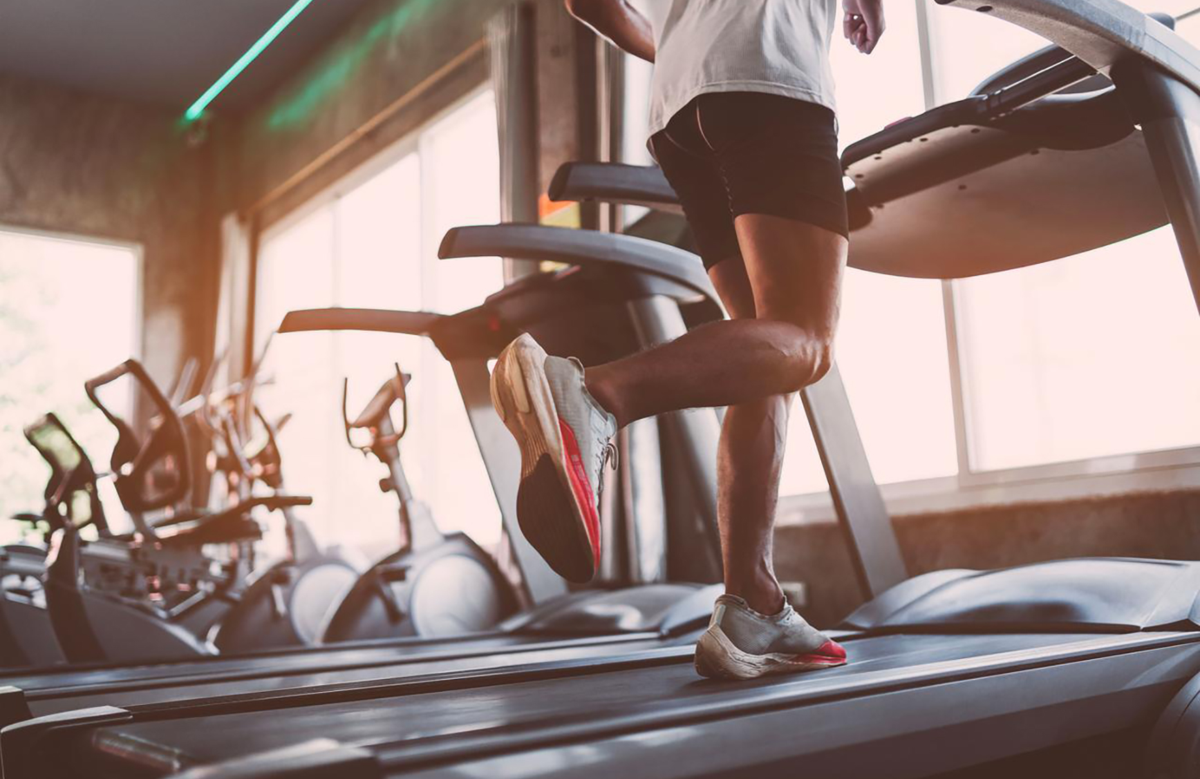 a shot of the back of a mans legs while running on a treadmill