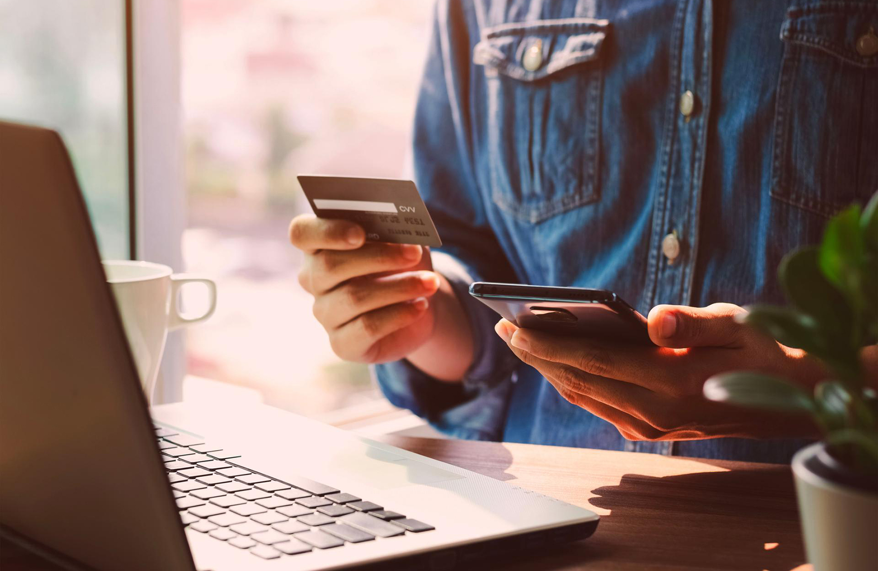 a man standing infront of a computor reading off of his credid card