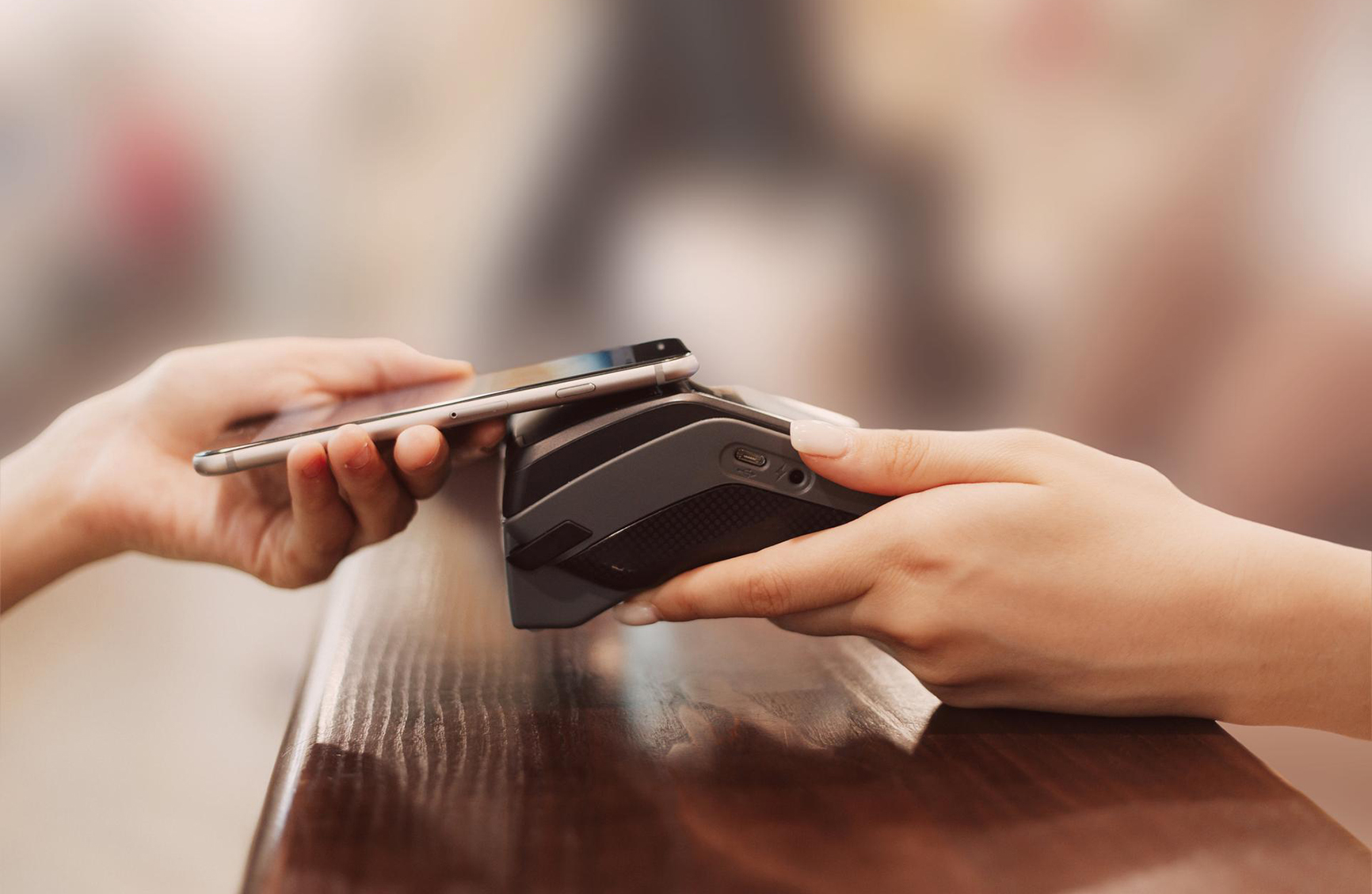 a hand emerging from the left side hlding a credit card